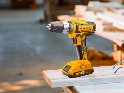 Taladro inalámbrico amarillo en una superficie de trabajo de madera, para proyectos de construcción y bricolaje.