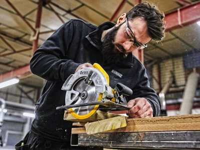 Hombre utilizando una sierra circular para cortes precisos en madera en un taller.