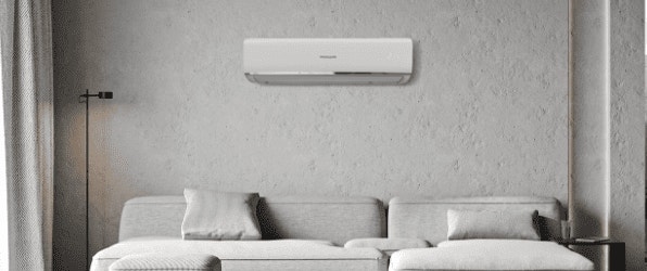 Sala de estar moderna con sofá gris, aire acondicionado en la pared y lámpara de pie.