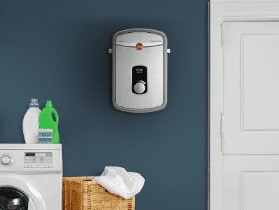 Cuarto de lavado con calentador de agua montado en la pared, lavadora y productos de lavandería.