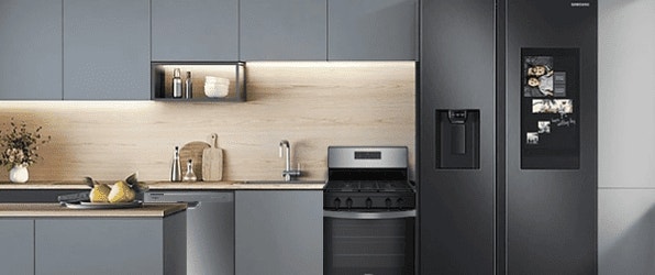 Cocina moderna con gabinetes grises elegantes, electrodomésticos empotrados y un refrigerador Samsung negro con pantalla digital.