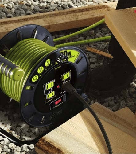 Carrete de cable eléctrico con tomacorrientes en un área de construcción.