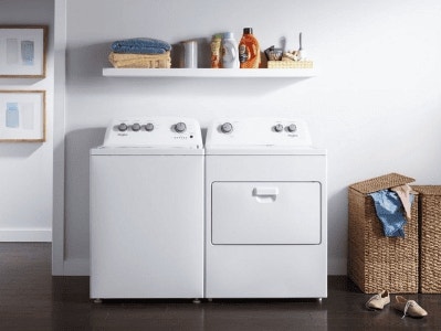 Cuarto de lavado con lavadora y secadora blancas, estante superior con productos de limpieza y canasta de mimbre.
