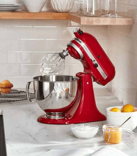 Batidora de pedestal roja en una cocina con ingredientes para repostería
