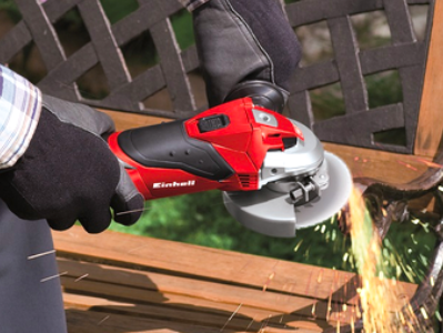 Amoladora de mano roja en uso para cortar metal, generando chispas en una superficie de trabajo.