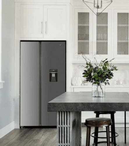 Refrigeradora de dos puertas en una cocina moderna con muebles blancos.