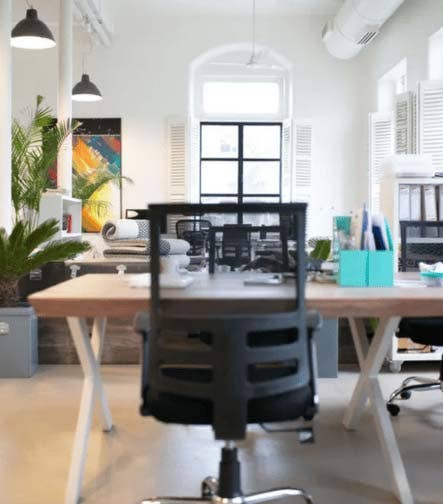Oficina moderna con escritorio de madera y silla ergonómica negra.